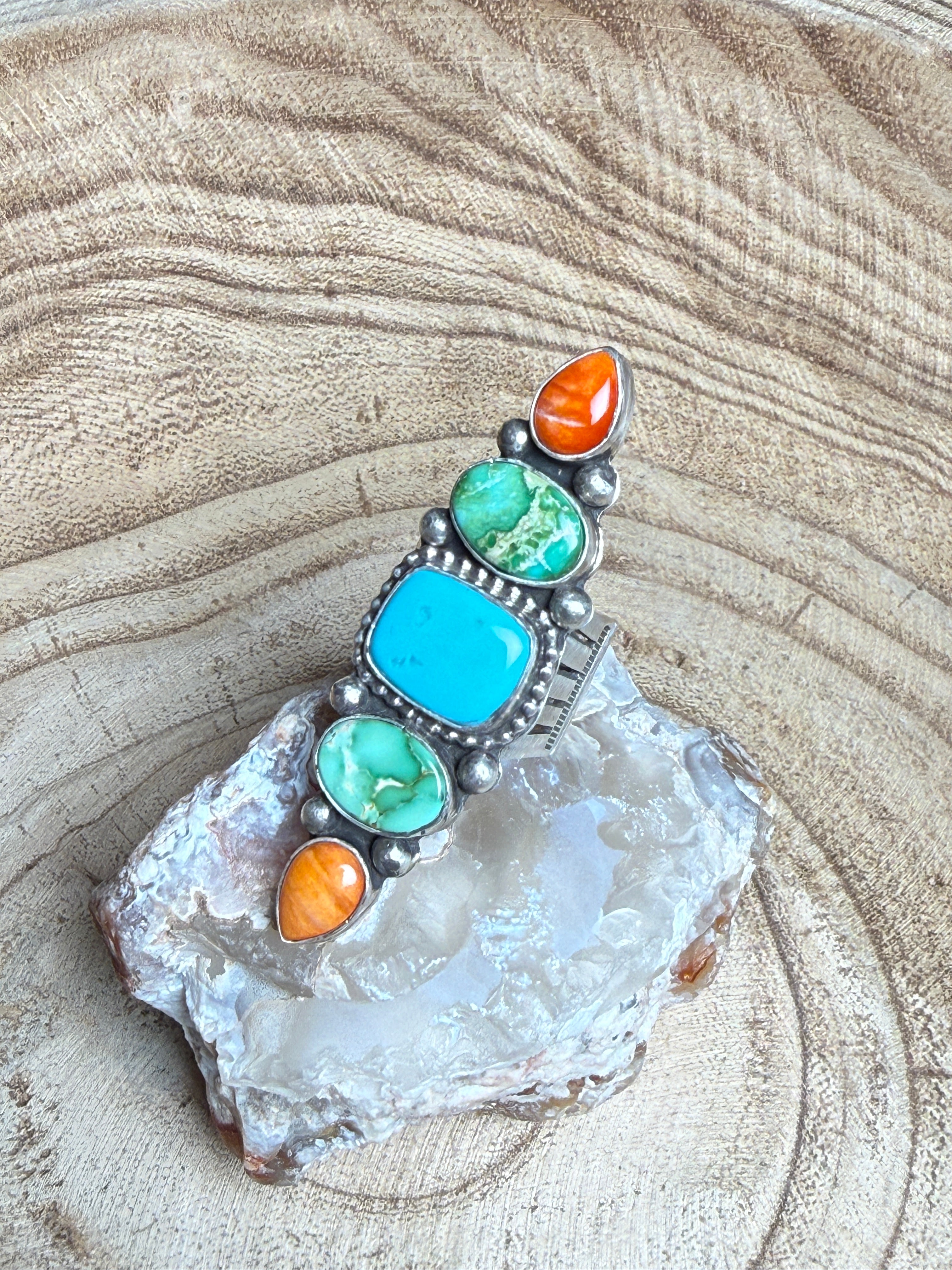 Jewelry with turquoise and orange stones on a textured stone surface