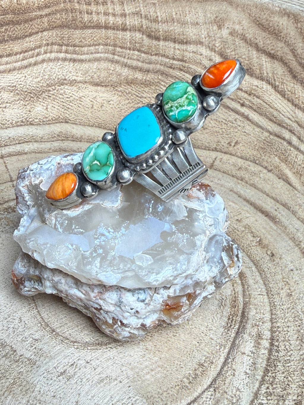 Silver pendant with colorful stones on a crystal rock