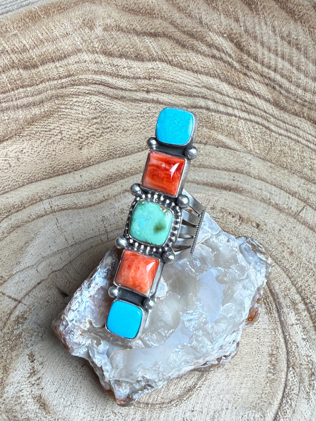 Silver bracelet with turquoise and coral stones on a crystal background