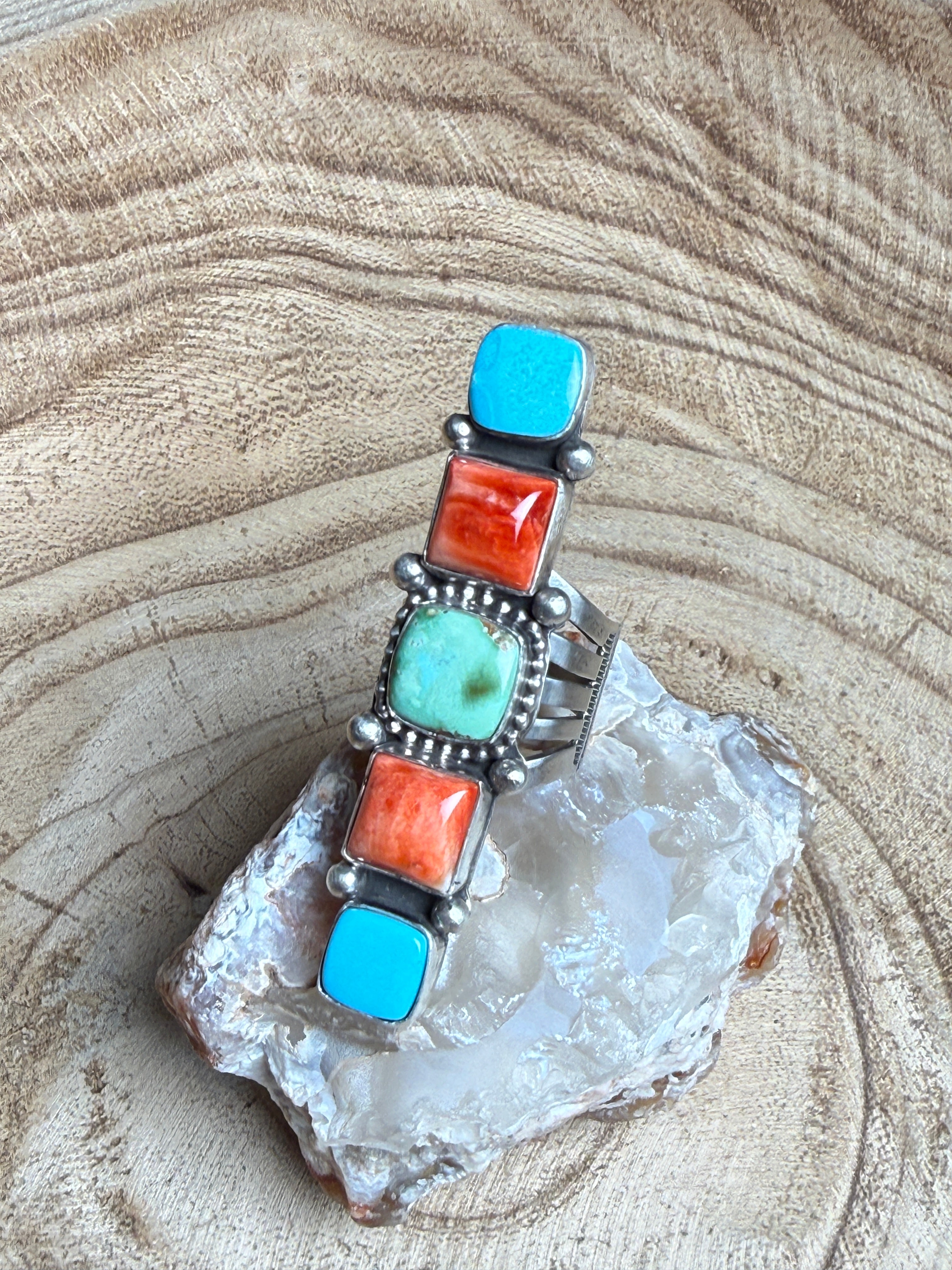 Silver bracelet with turquoise and coral stones on a crystal background
