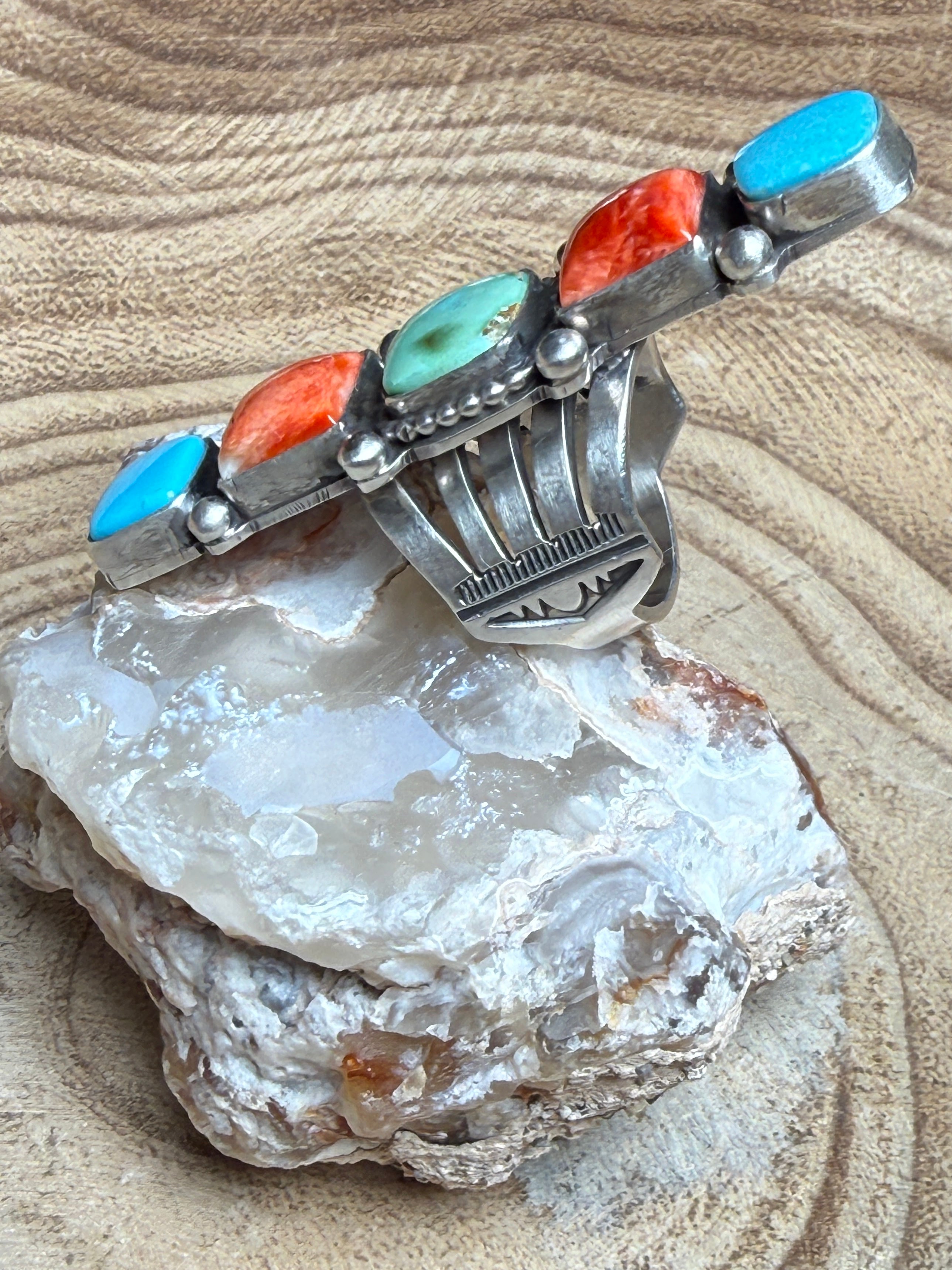 Silver ring with turquoise and coral stones on a rock