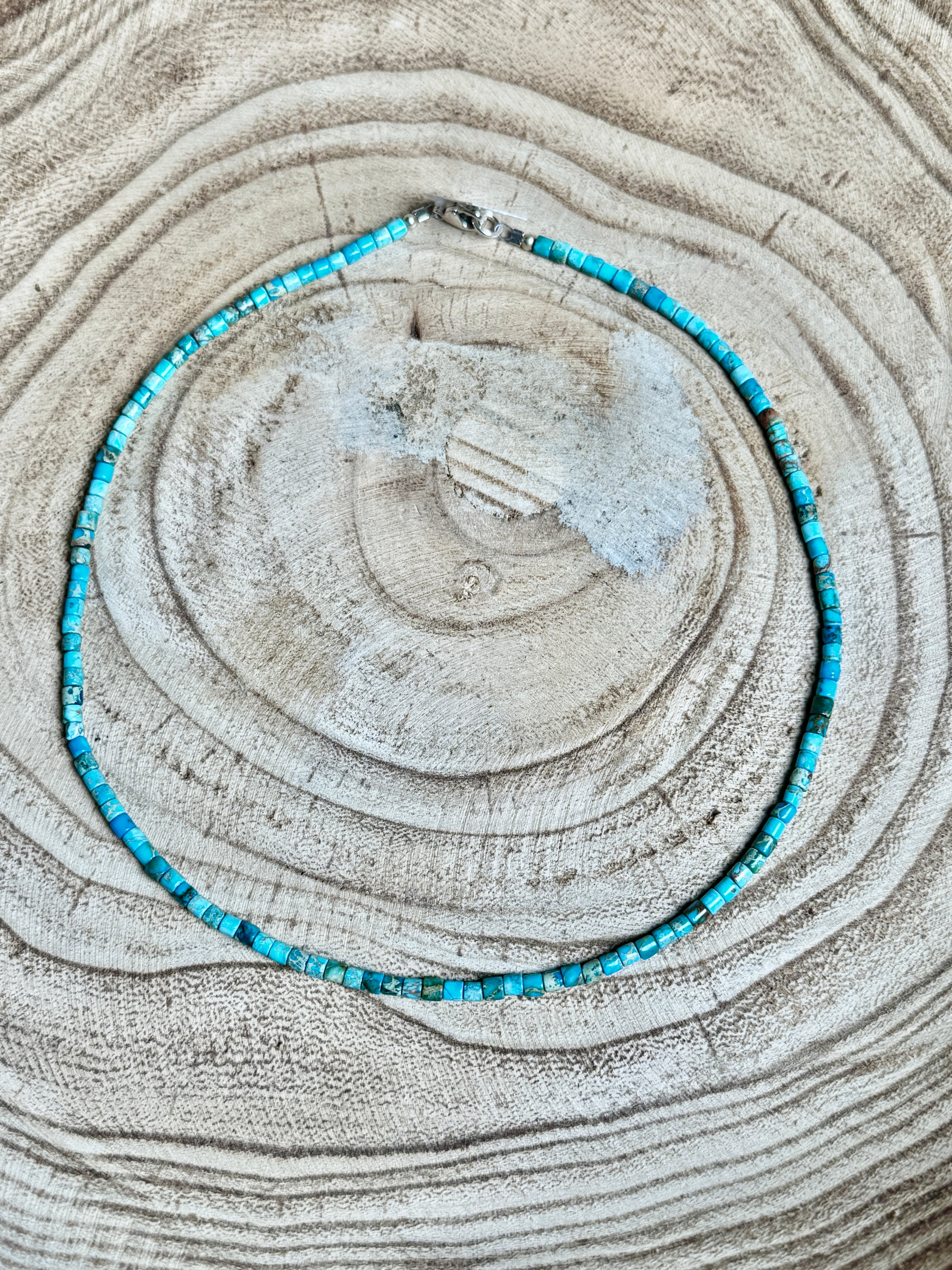 Turquoise beaded necklace on a textured beige surface