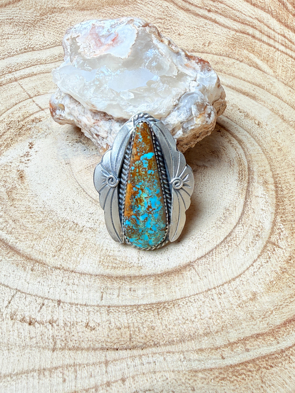 Silver ring with turquoise stone on a wooden surface