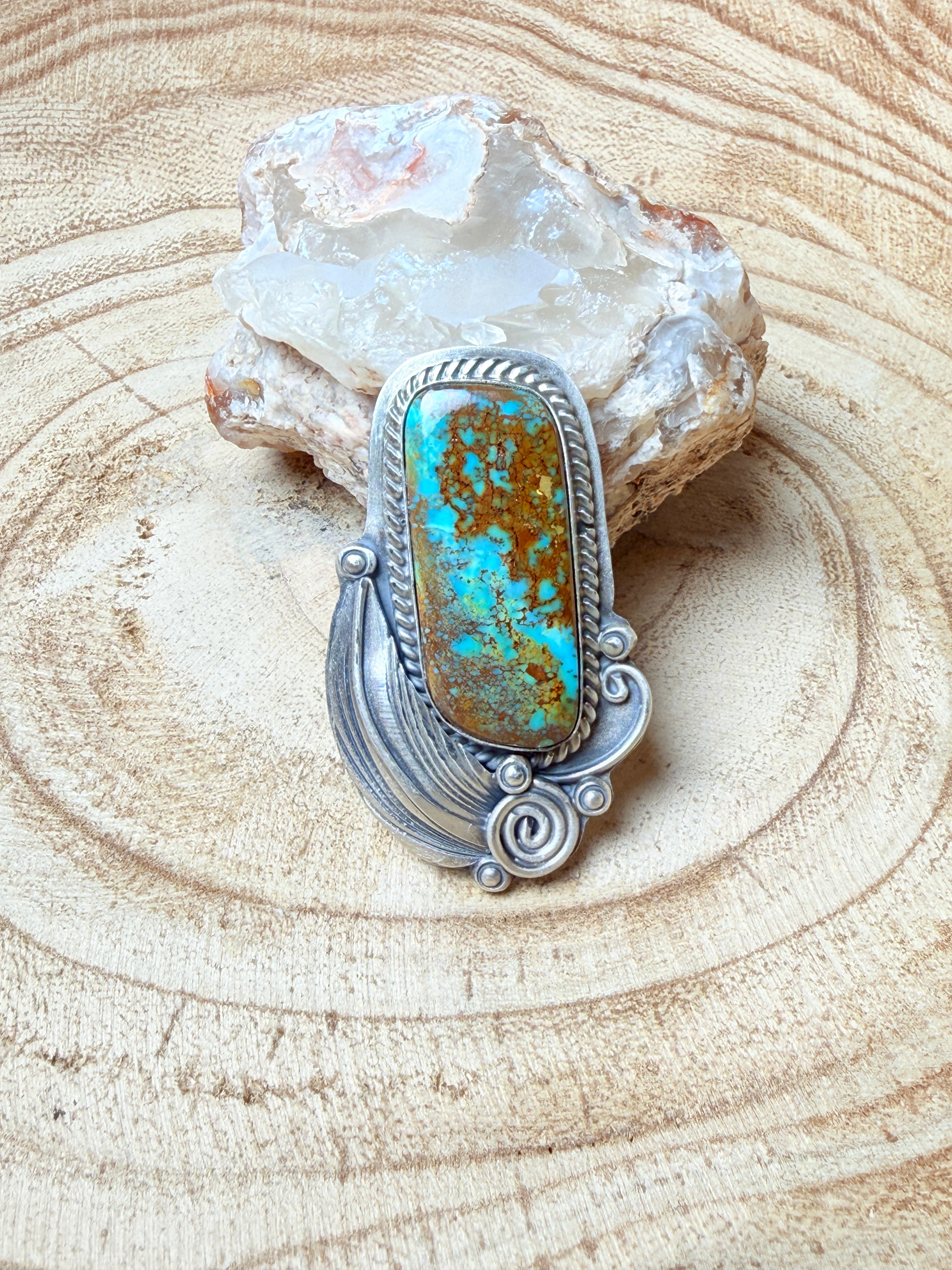 Silver ring with a turquoise stone on a wooden surface