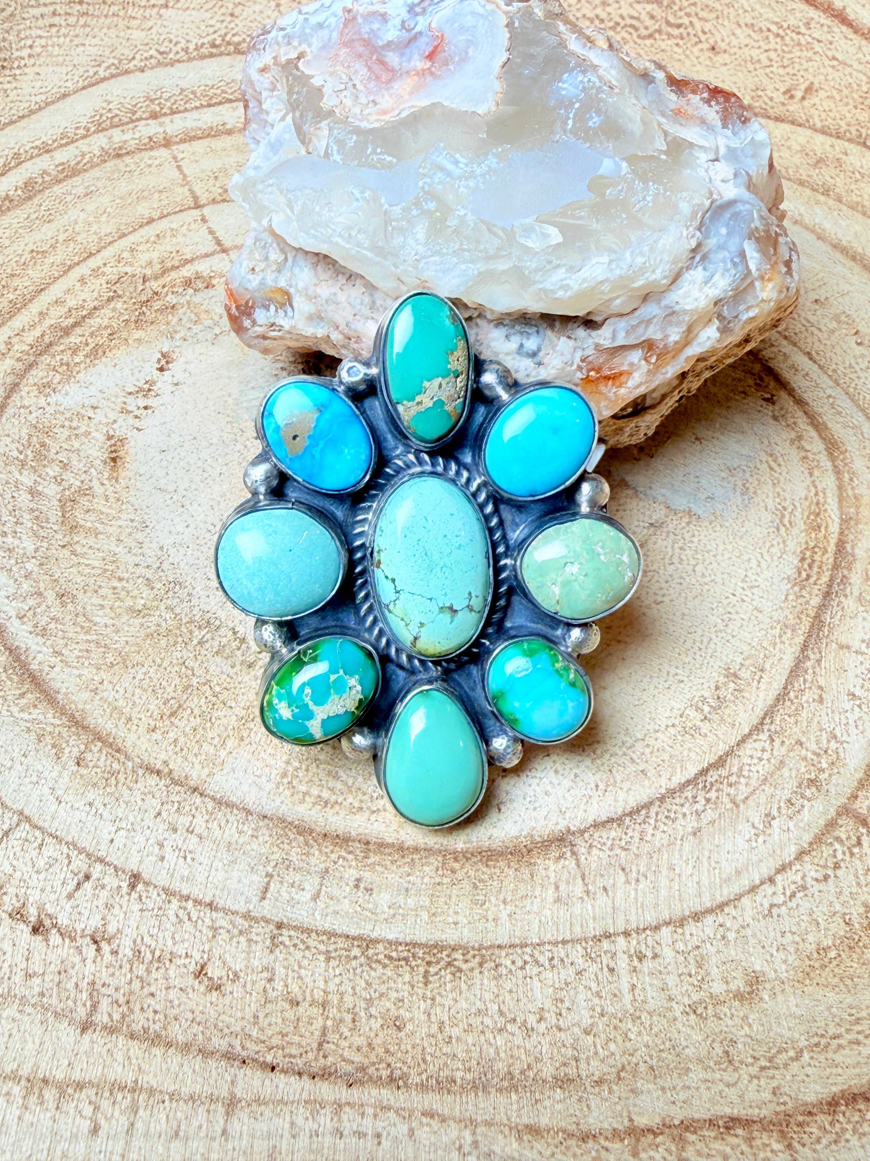 Turquoise and sterling silver ring next to mineral rock on beige surface