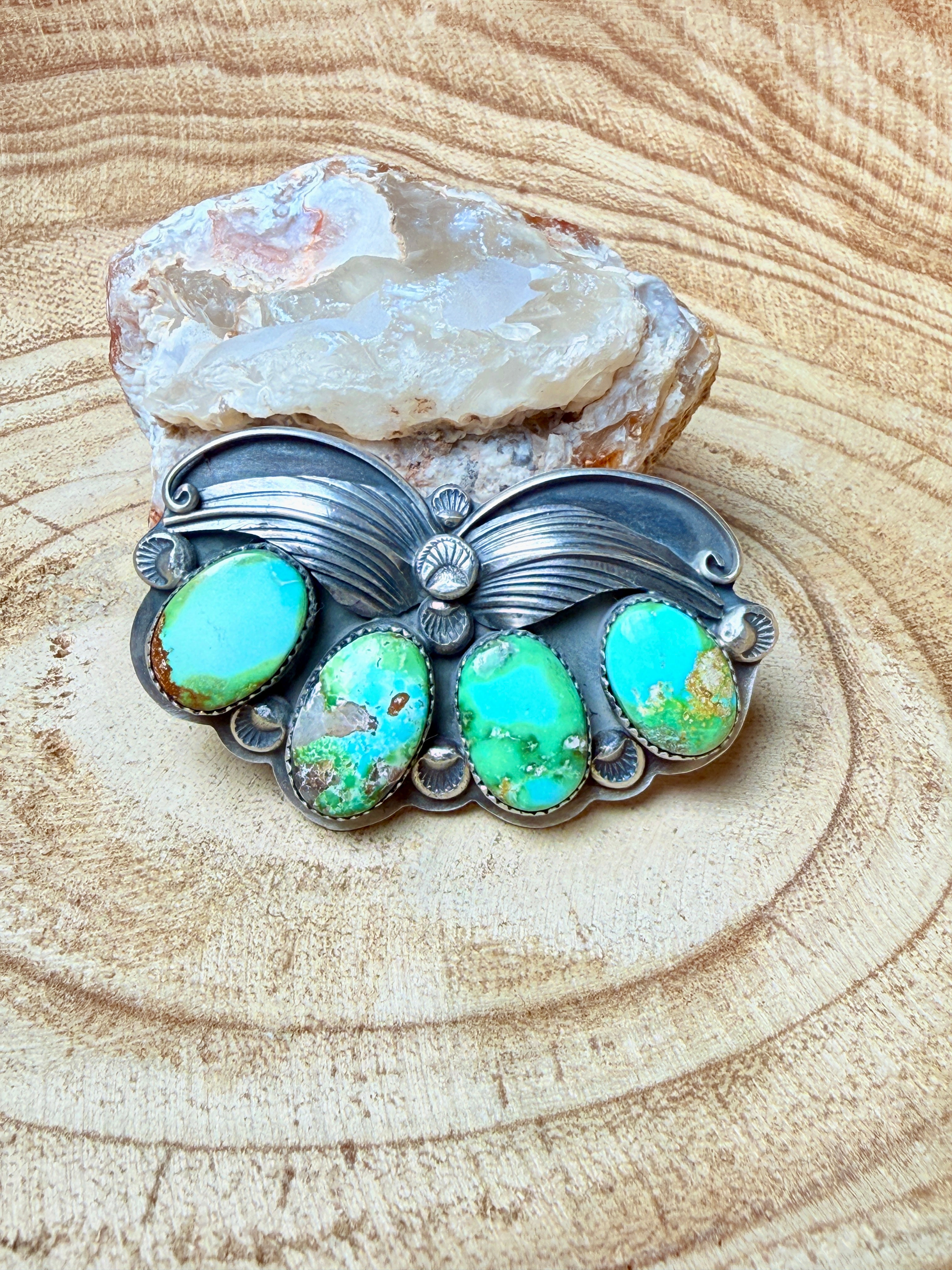 Silver butterfly-shaped pendant with turquoise stones on a wooden surface