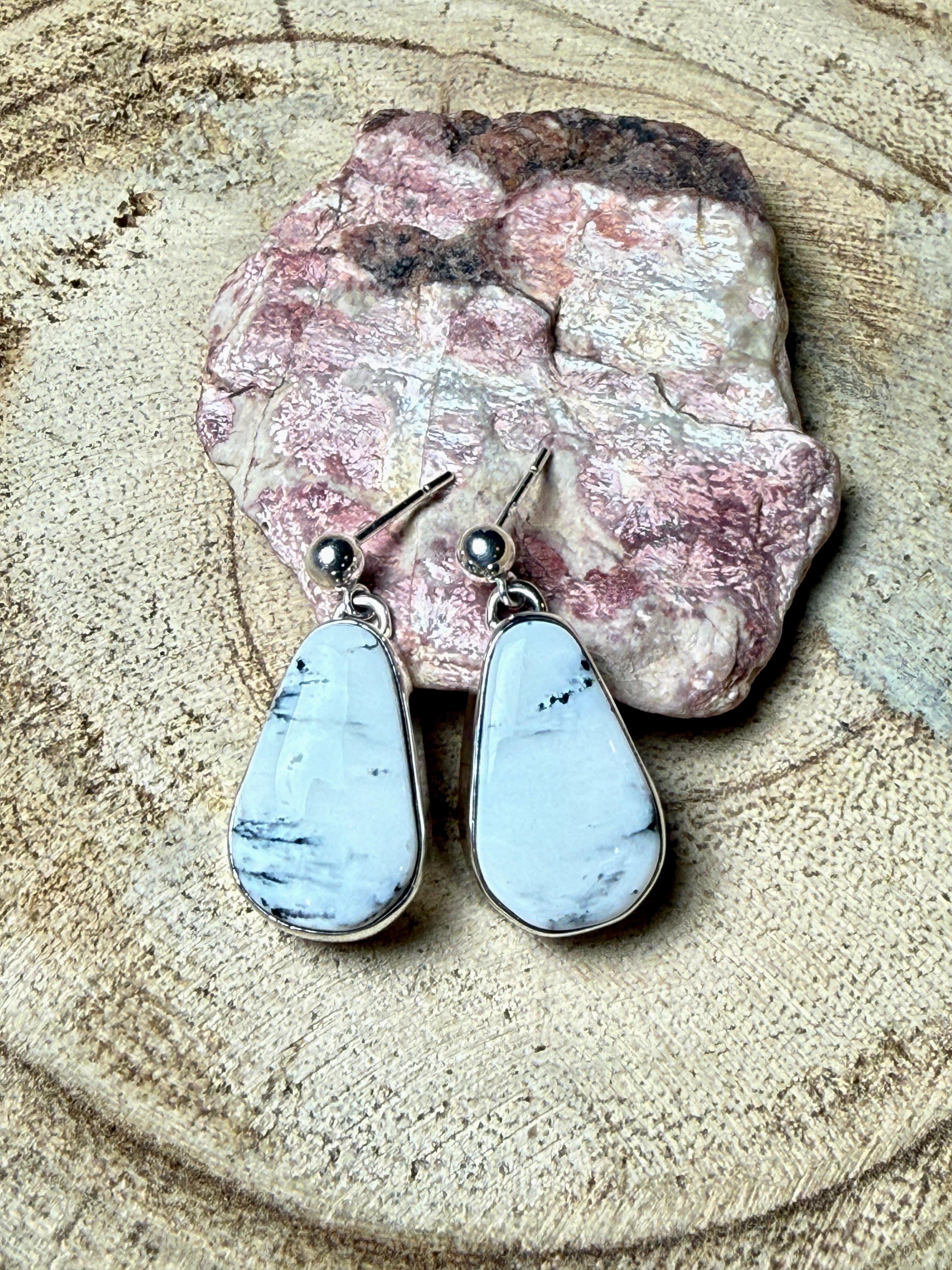 Teardrop-shaped earrings on a stone surface