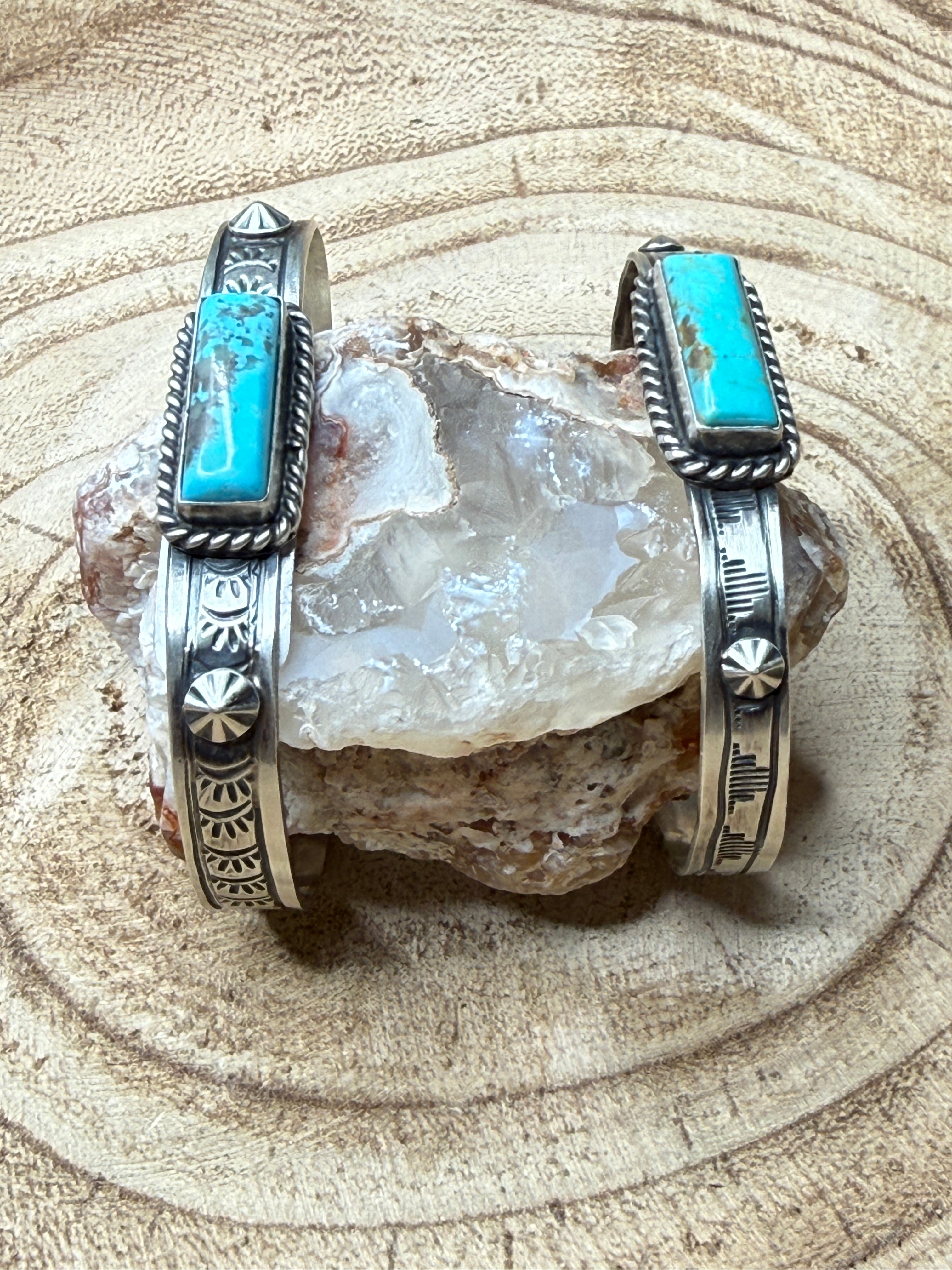 Two silver bracelets with turquoise stones on a rock