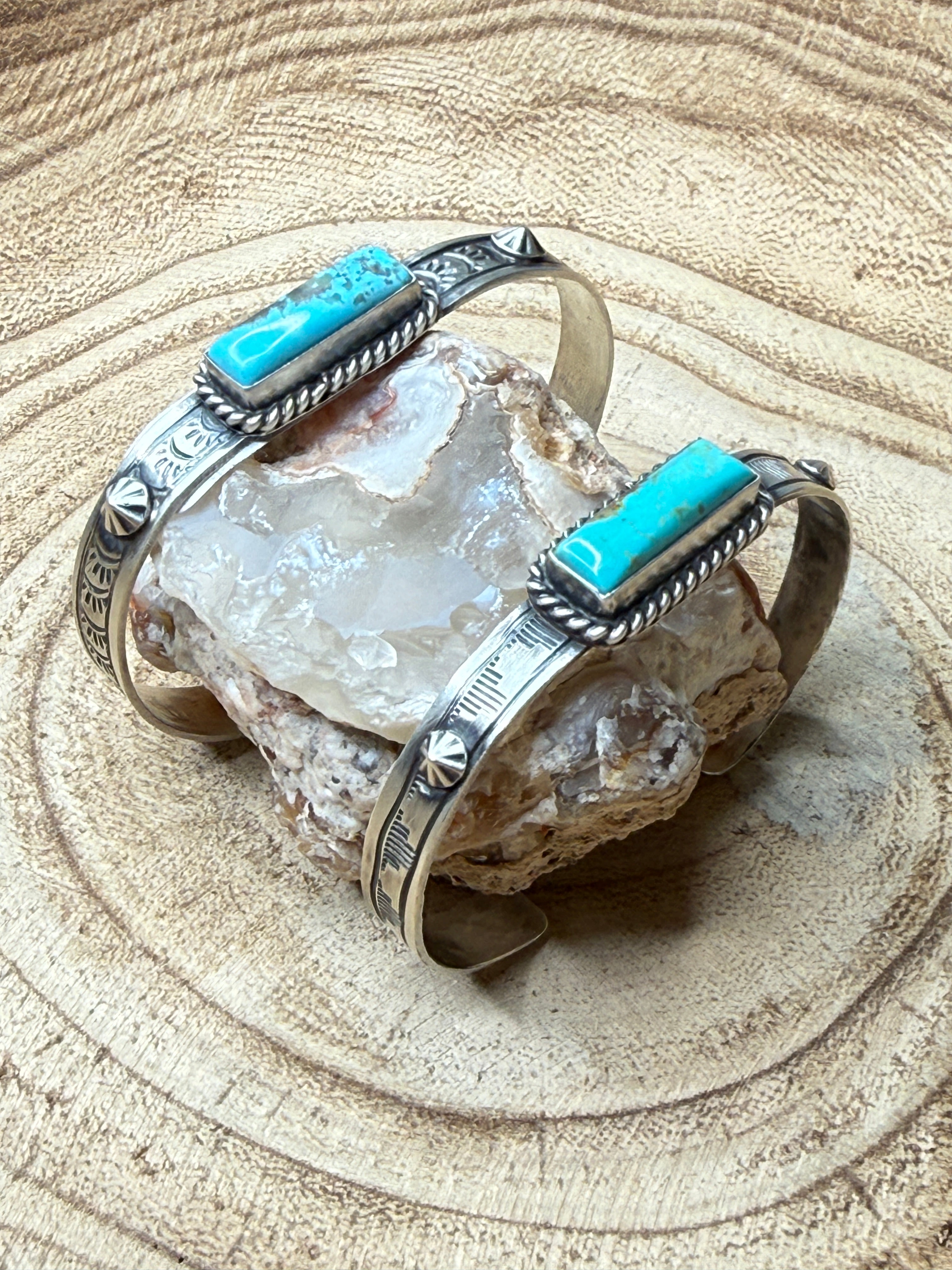Silver cuff bracelet with turquoise accents on a crystal rock
