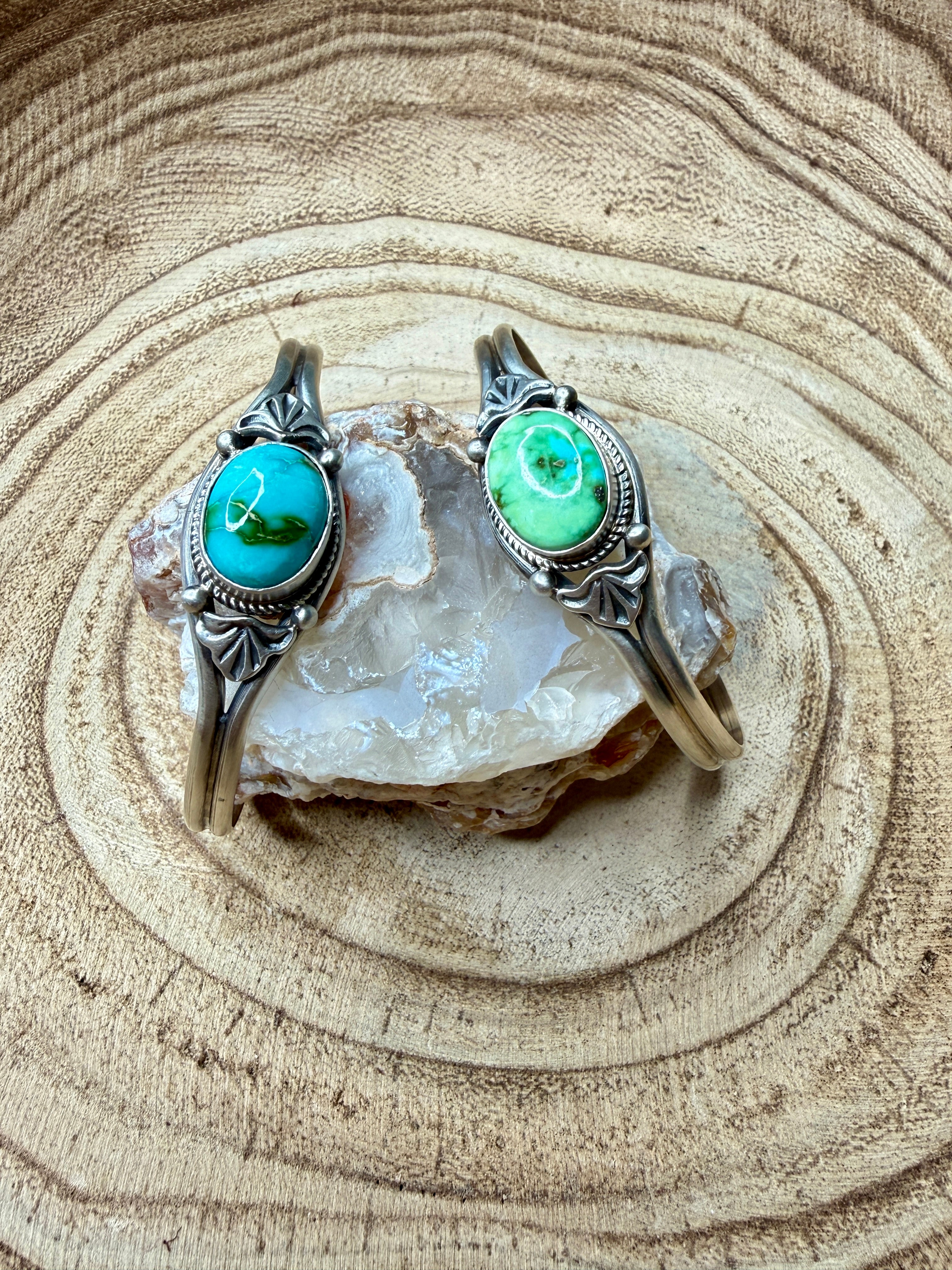 Two silver rings with turquoise stones on a piece of crystal rock.
