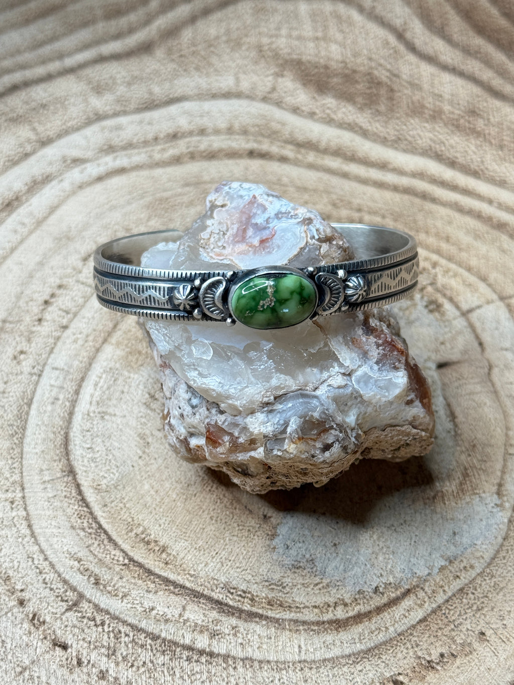 Silver bracelet with a green stone on a rock
