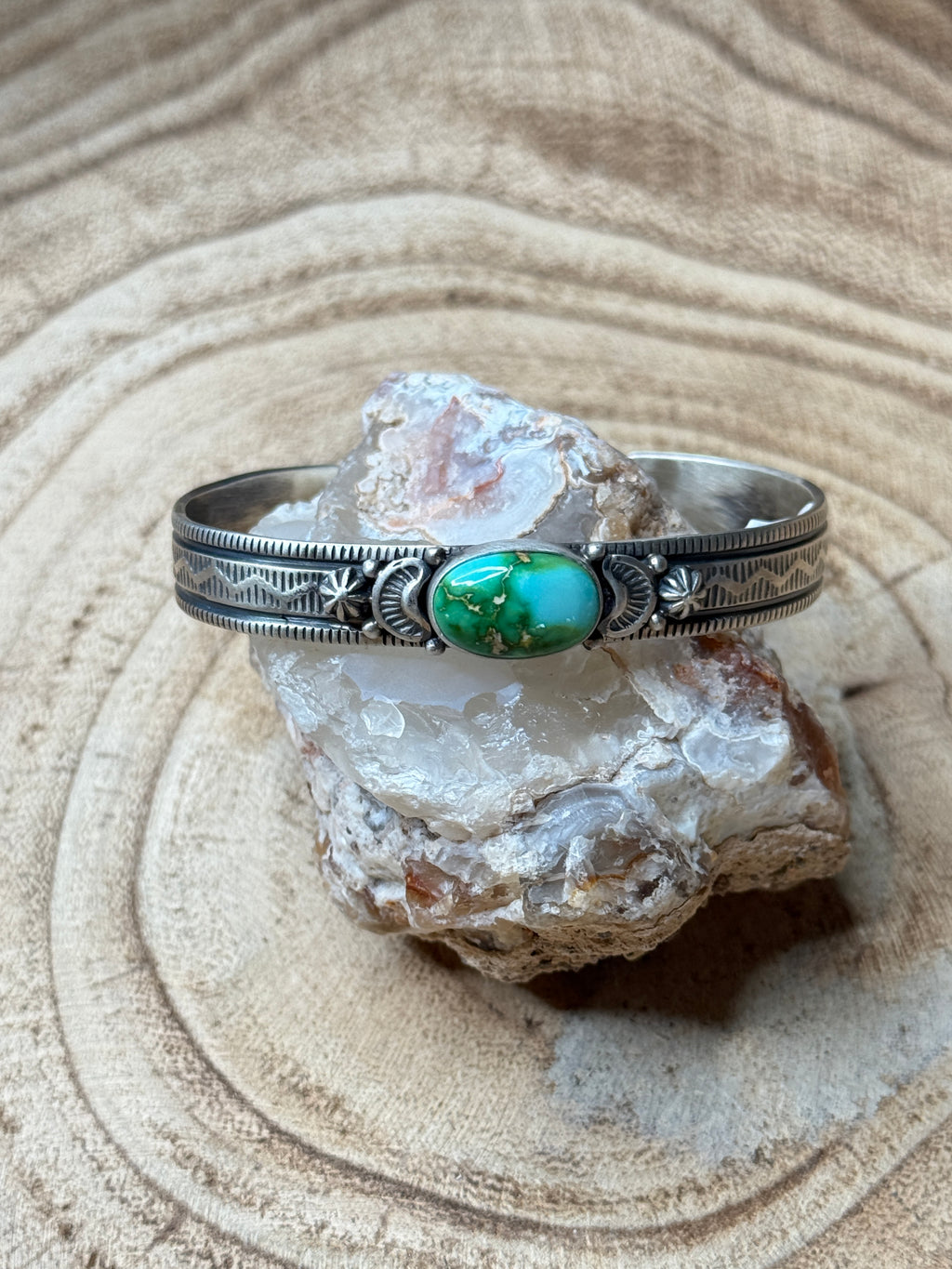 Silver ring with a green stone on a rock