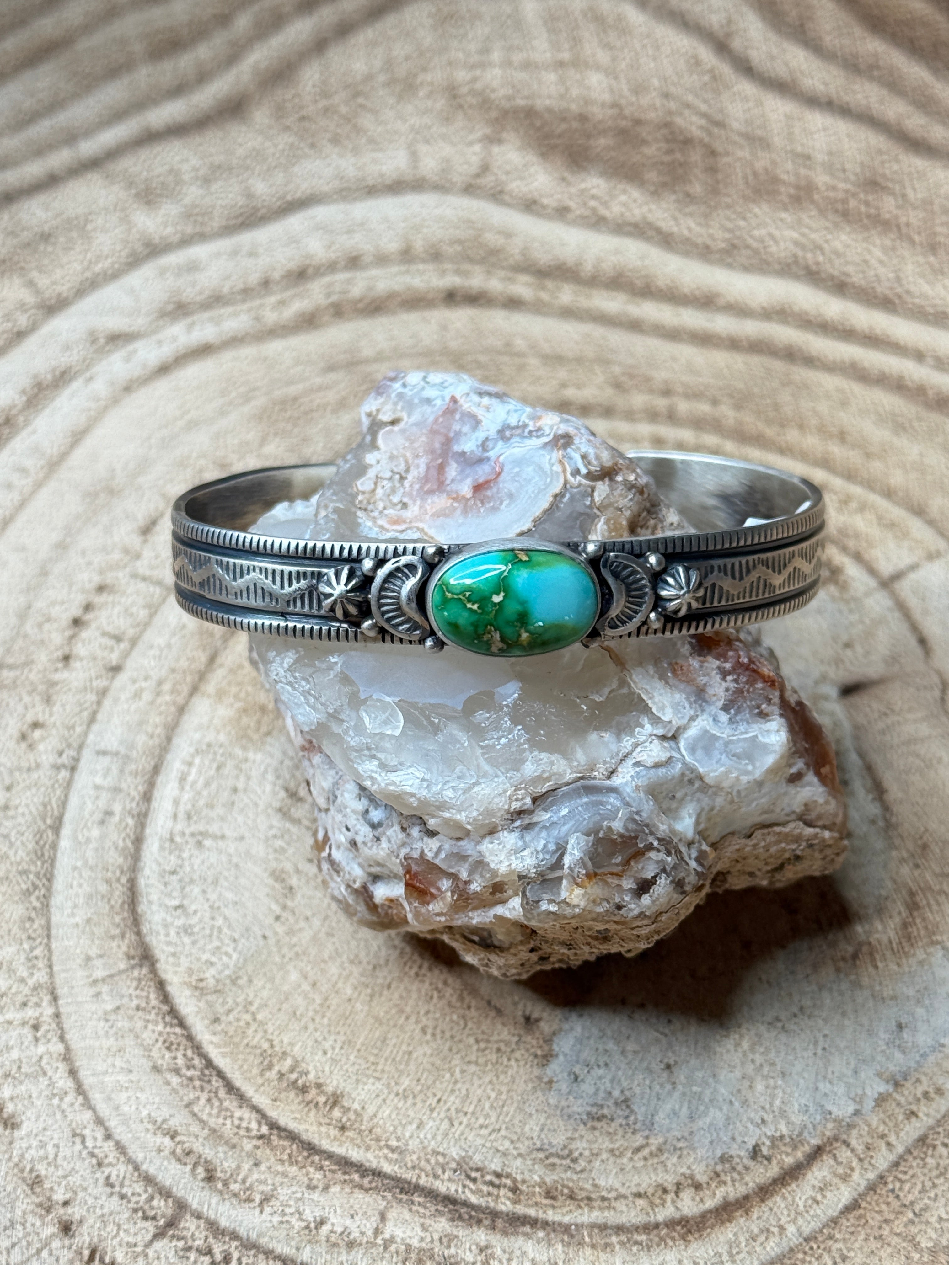 Silver ring with a green stone on a rock