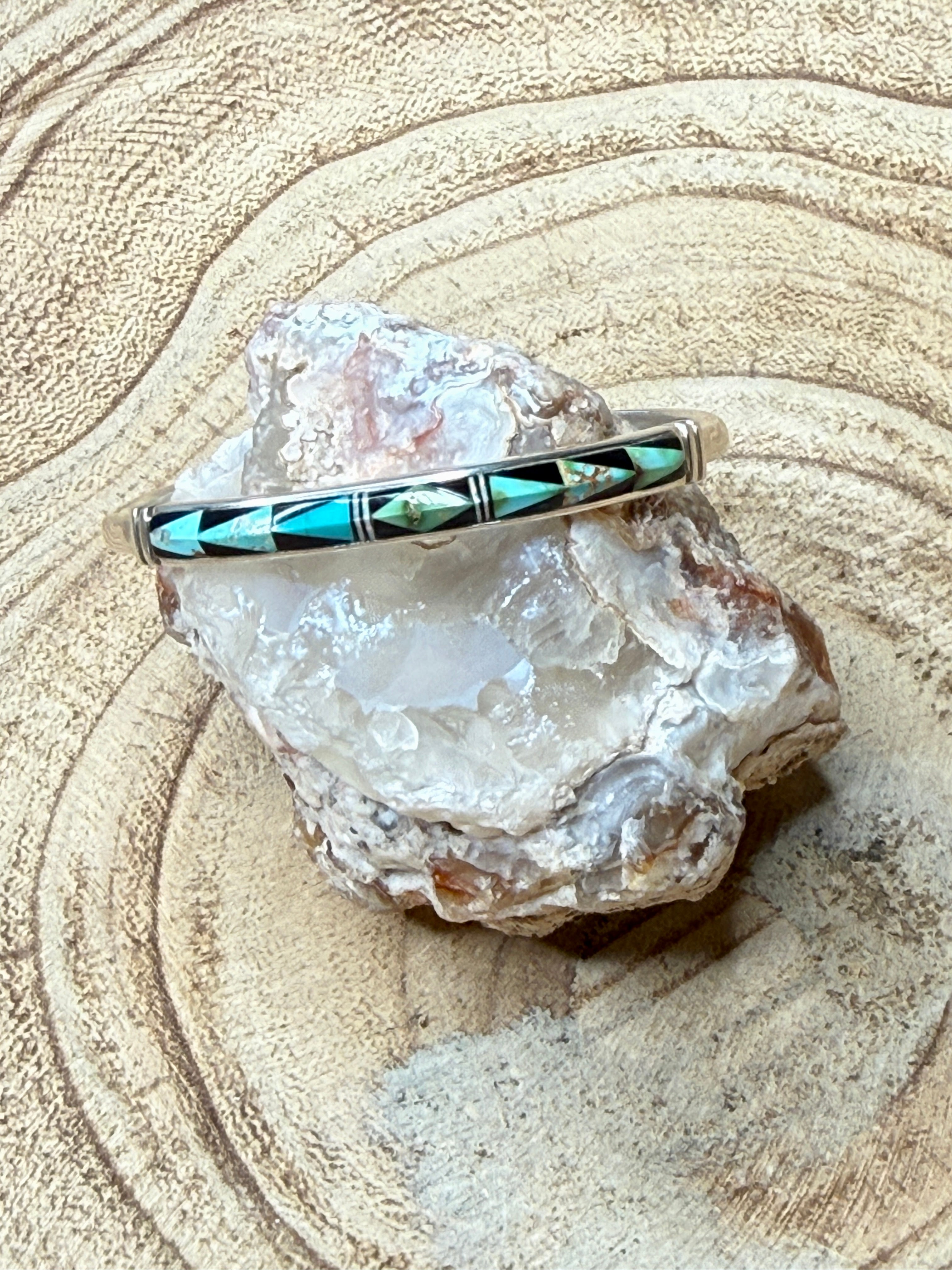 Bangle with turquoise stones on a crystal rock against a sandy background