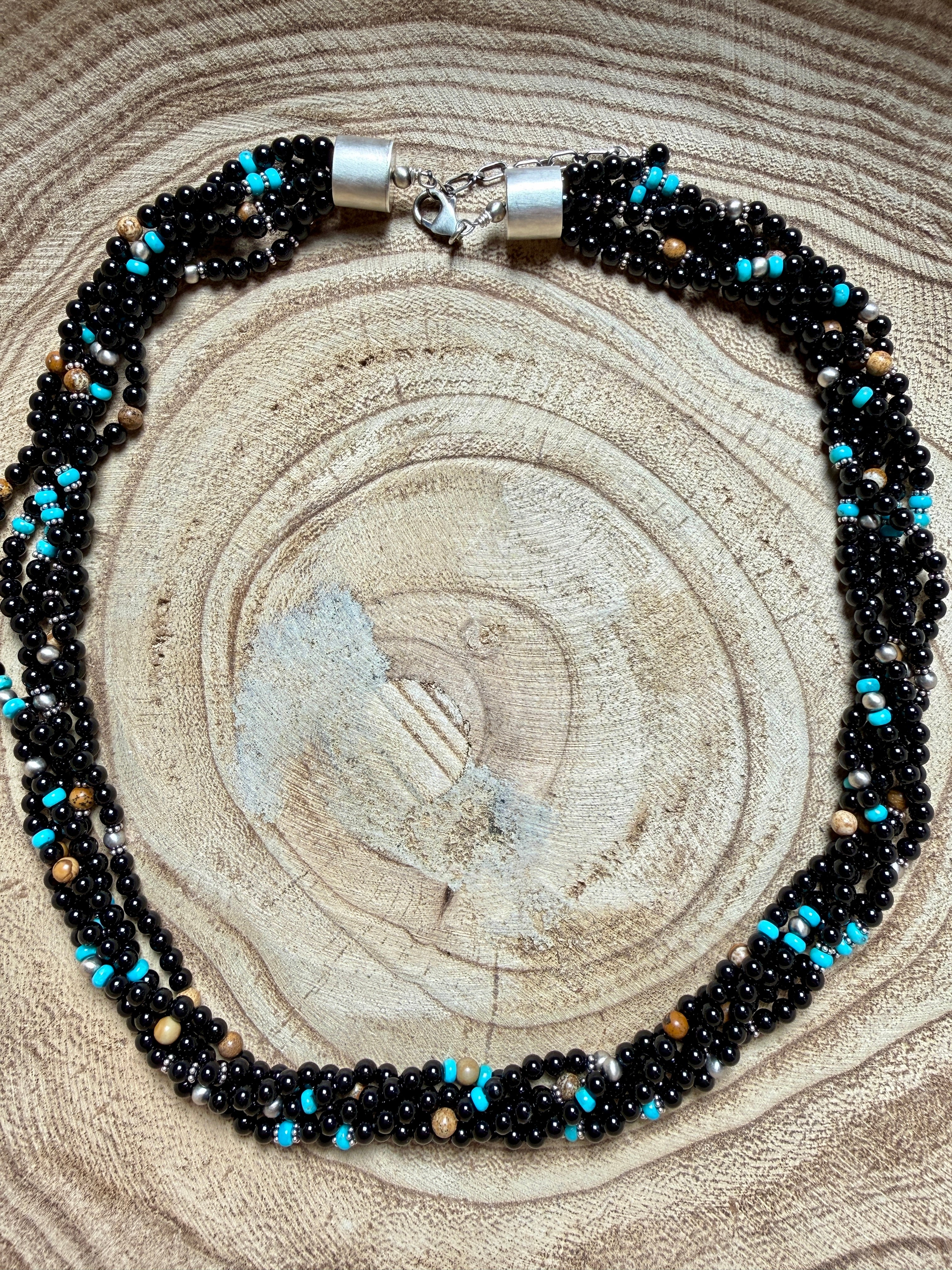 Beaded necklace with black, blue, and silver beads on a wooden surface