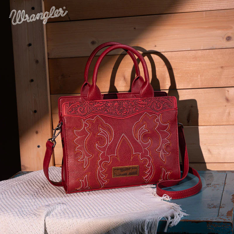 Red handbag with intricate designs on a wooden surface, featuring the Wrangler brand.