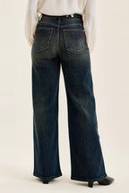 Dark blue jeans worn by a person on a plain background