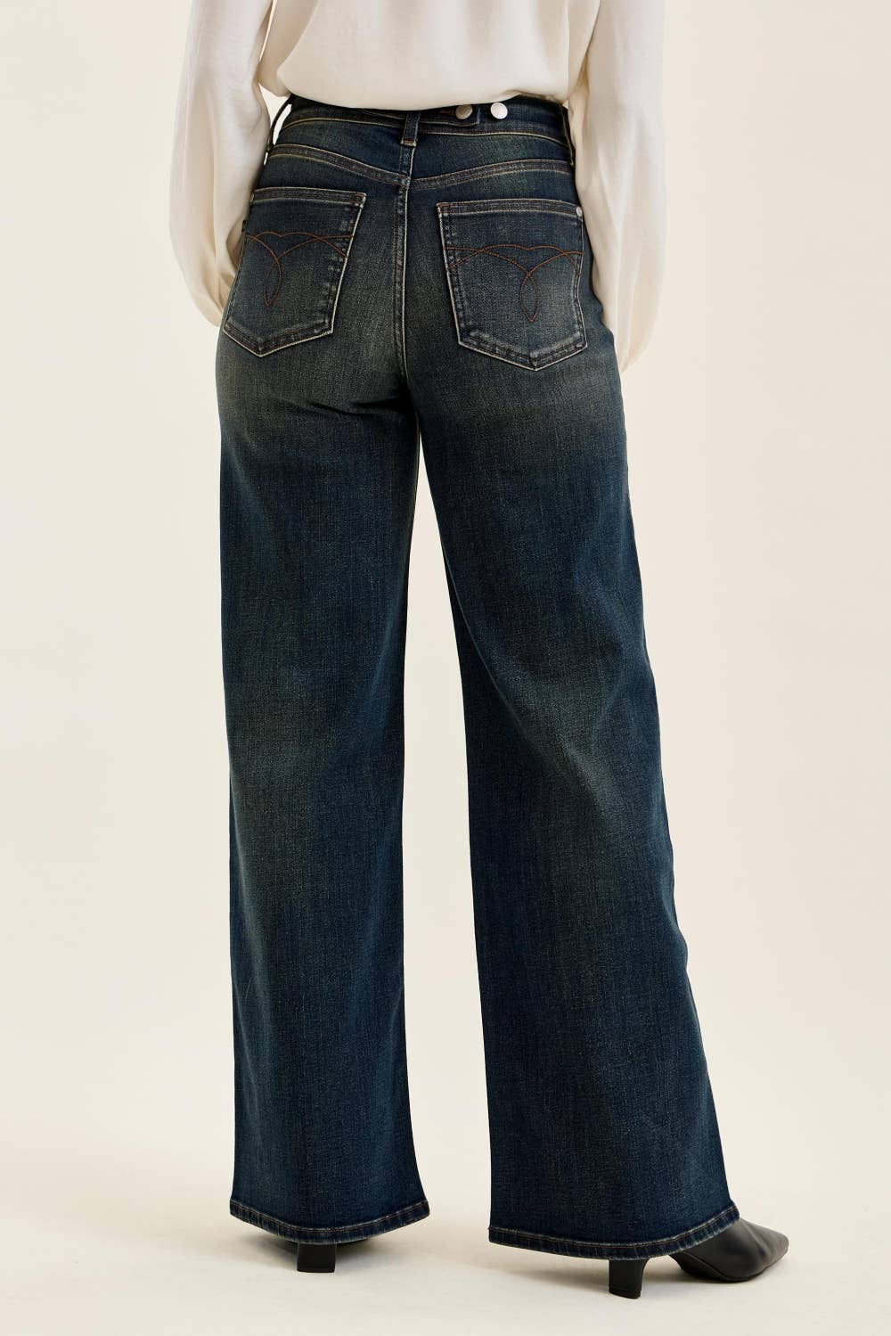 Dark blue jeans worn by a person on a plain background