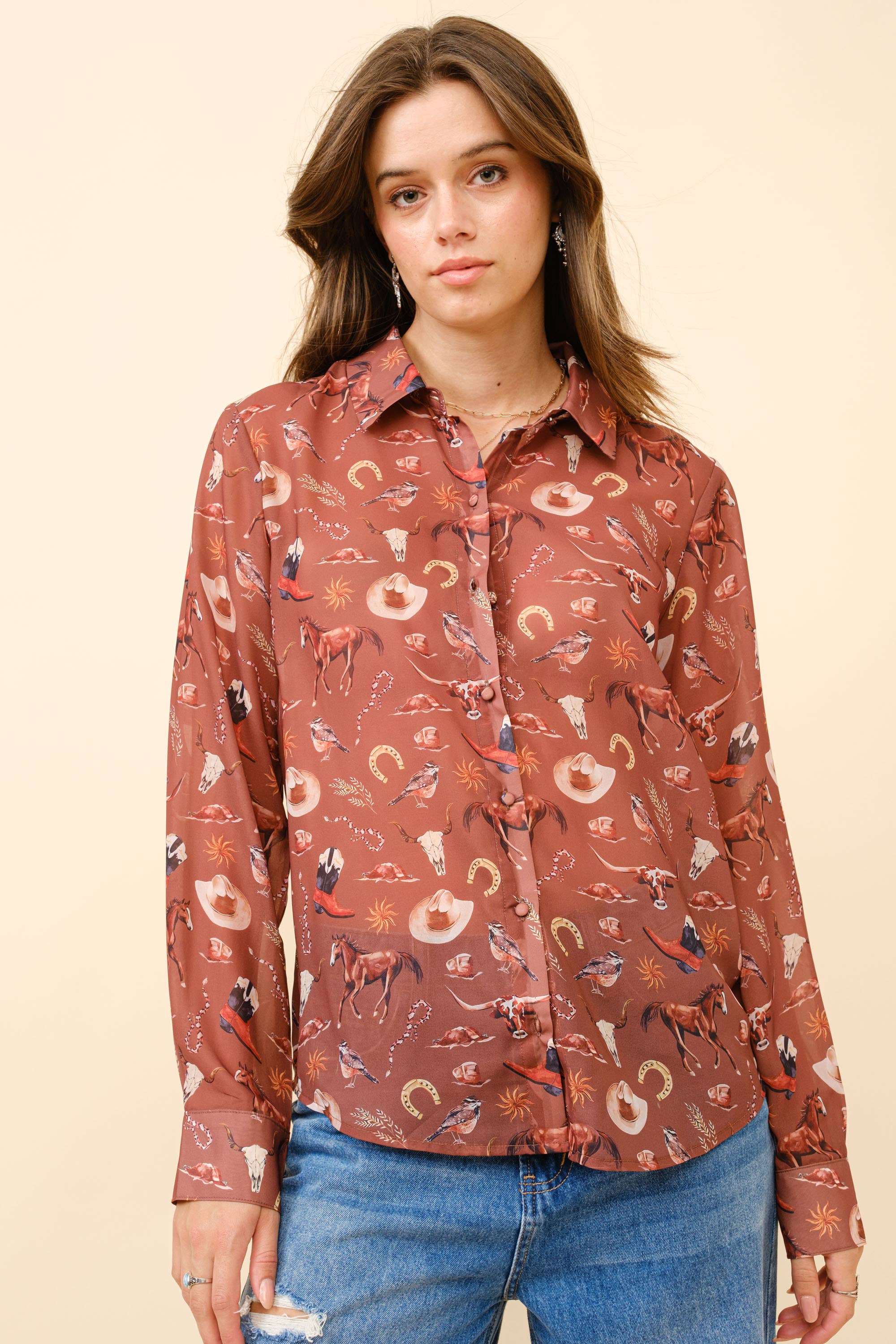 Woman wearing a patterned shirt with long sleeves and blue jeans on a beige background