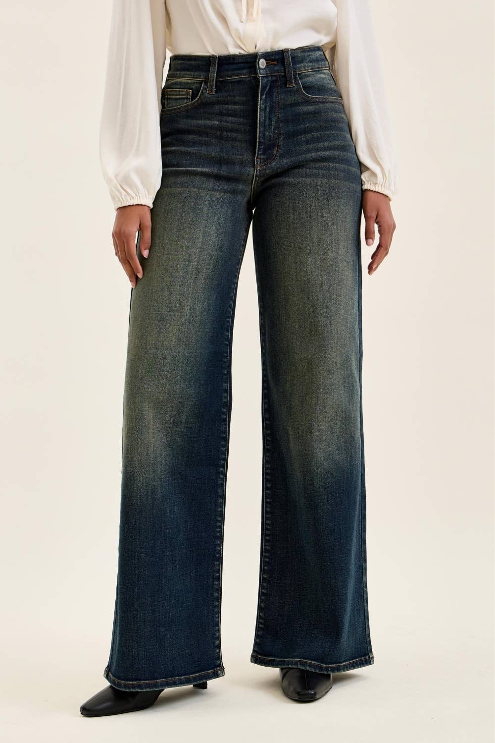 Person wearing dark blue wide-leg jeans on a plain background