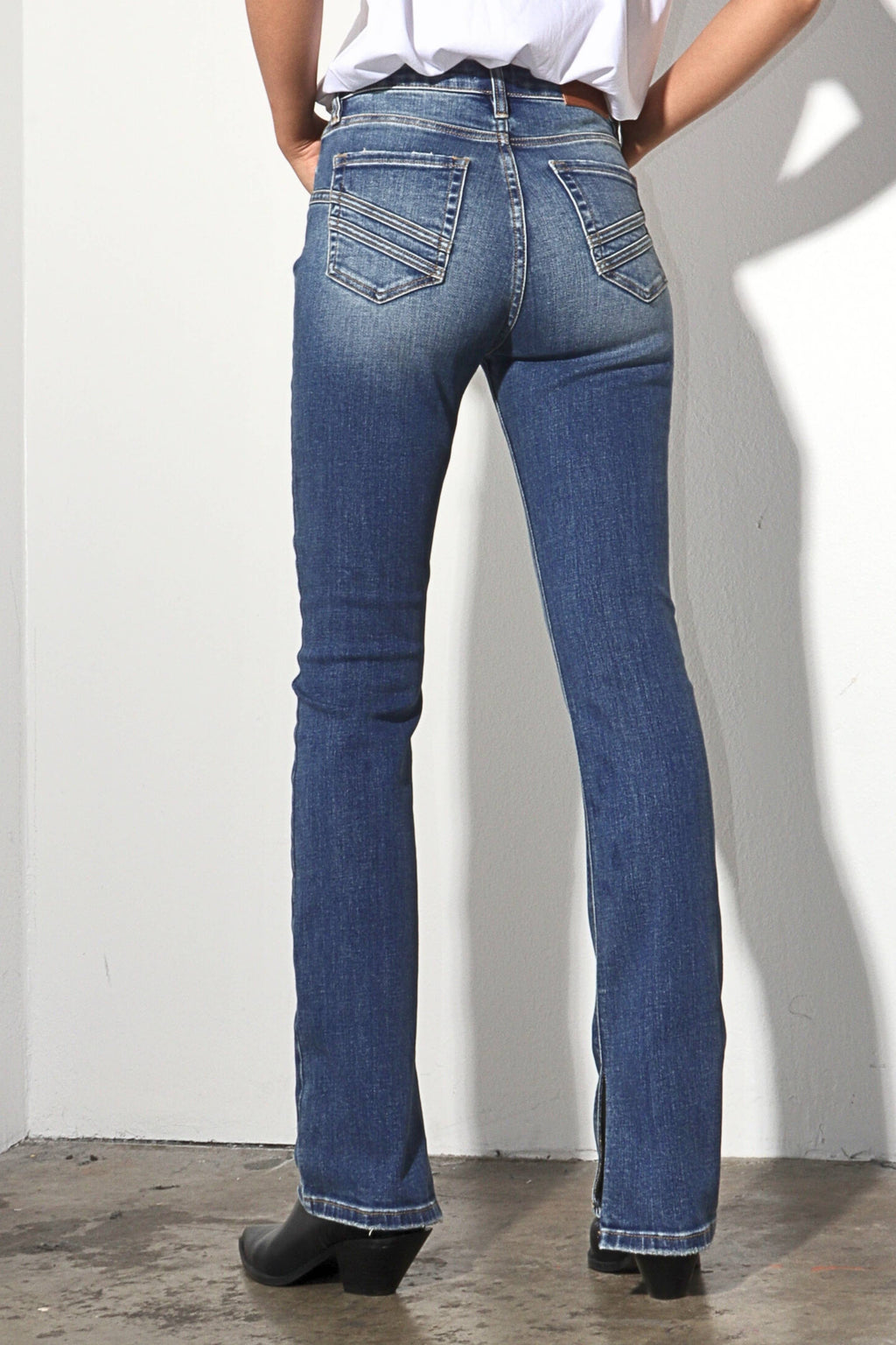 Person wearing blue jeans against a white wall