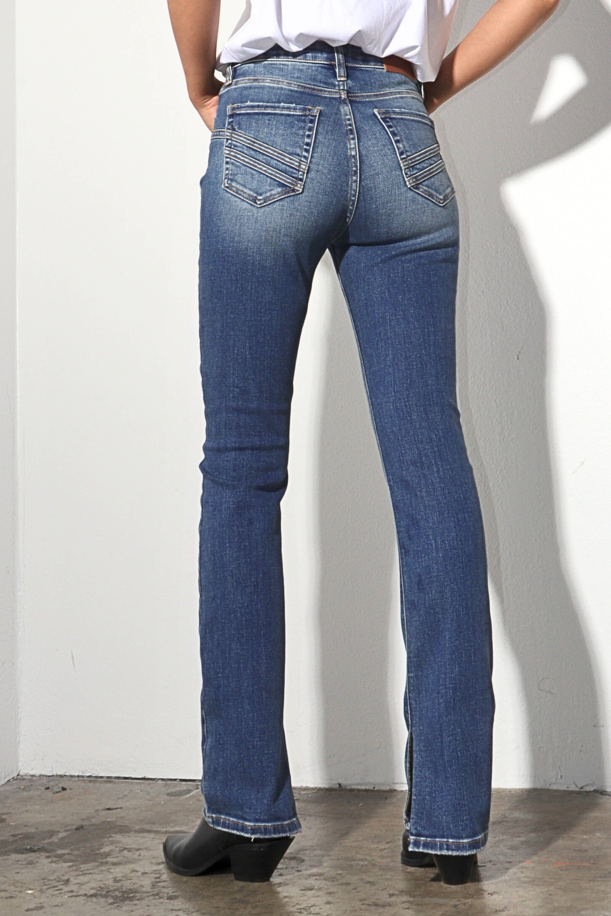 Person wearing blue jeans against a white wall
