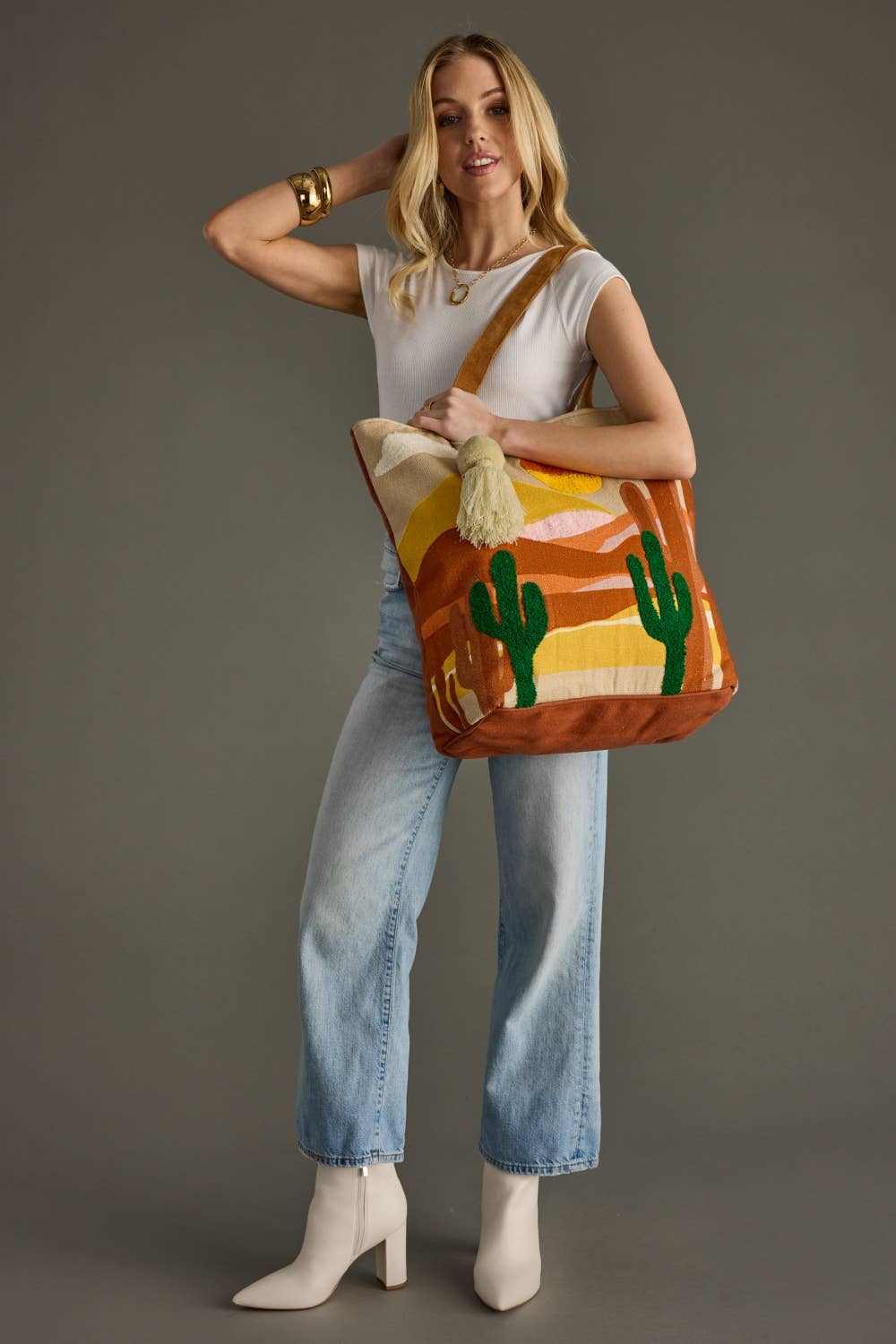 Woman holding a colorful bag with cactus design against a gray background