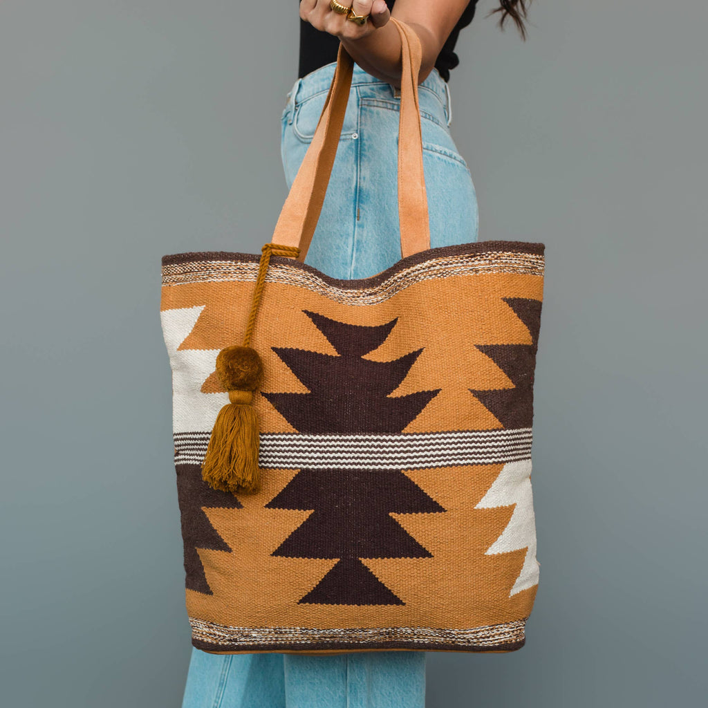 Tote bag with geometric pattern held by a person against a gray background