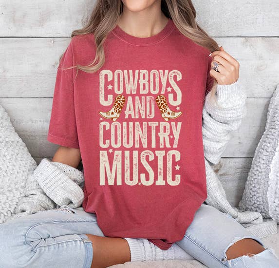 Person wearing a red shirt with 'Cowboys and Country Music' text, sitting on a wooden floor.