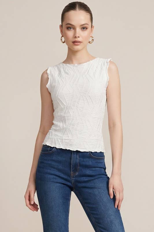 Woman wearing a white sleeveless top and blue jeans on a beige background