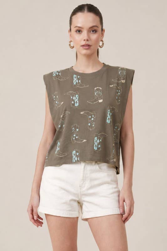 Woman wearing a sleeveless top with cowboy boot pattern and white shorts on a beige background