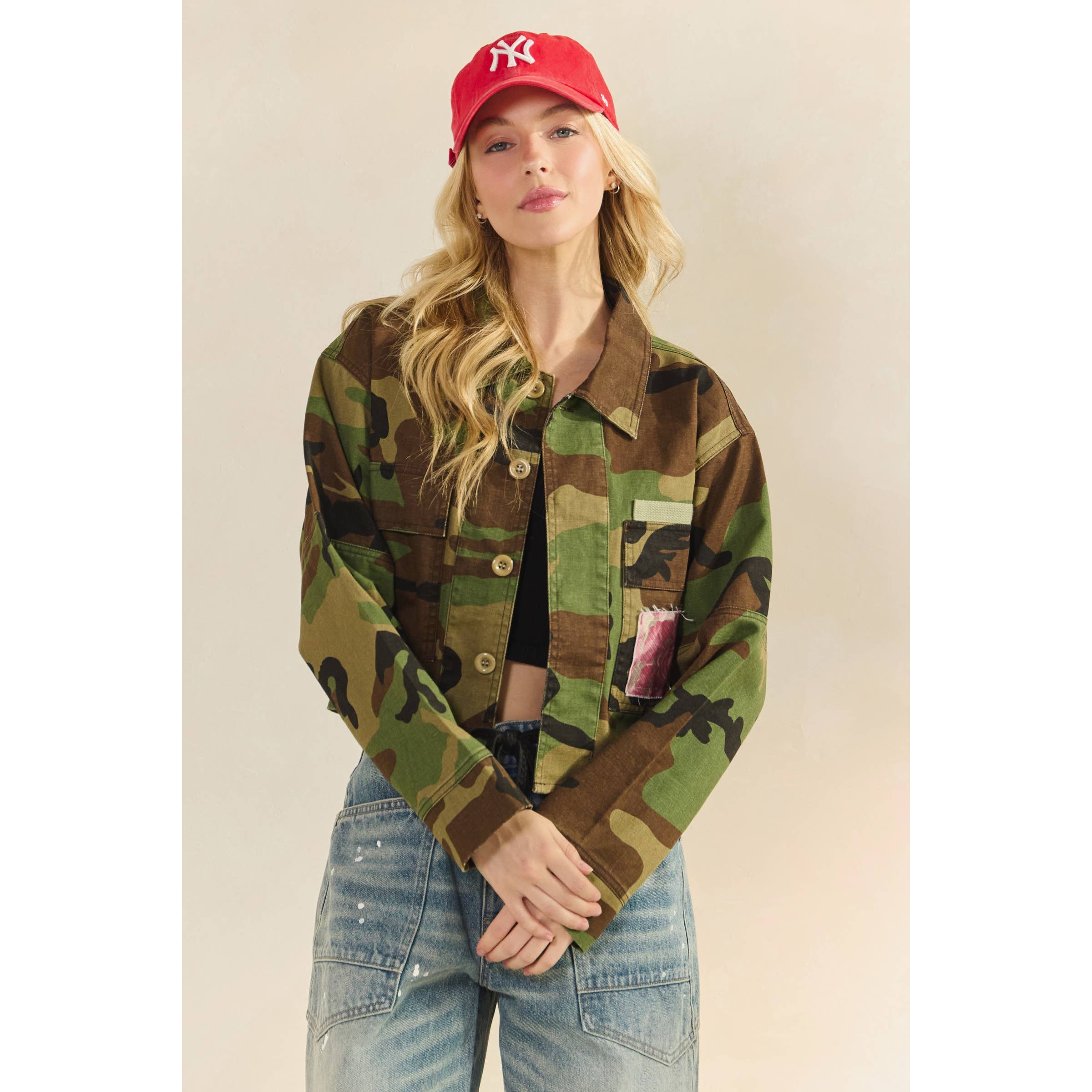 Person wearing a camouflage jacket and red cap on a beige background