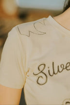 Beige t-shirt with 'Silver' text on a blurred background